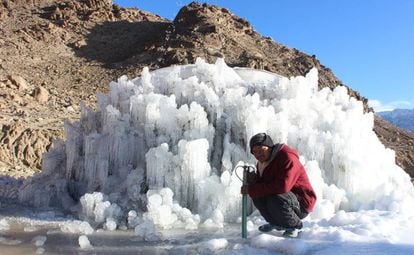 Trabalhador posa junto a uma estupa de gelo em processo de construção
