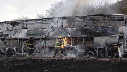 Bombeiros tentam apagar as chamas de um ônibus incendiado em Jalisco.
