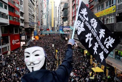 Manifestante mascarado ergue faixa em Hong Kong, neste domingo.