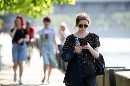 Mulher consulta telefone celular enquanto passeia em Moscou.
