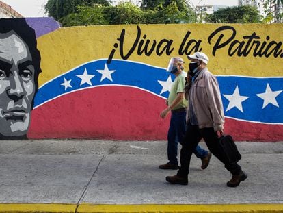 Dois homens passam em frente a um cartaz de Caracas, neste domingo.