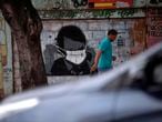 A man walks past a graffiti of Brazilian President Jair Bolsonaro wearing a face mask in downtown Rio de Janeiro, Brazil, on March 24, 2020 during the coronavirus COVID-19 pandemic. - The Rio de Janeiro state government is requesting people not to go to the beach or any other public areas as a measure to contain the coronavirus pandemic. (Photo by Mauro PIMENTEL / AFP)