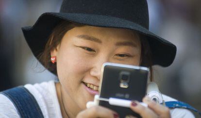 Uma turista asiática olha seu telefone celular.