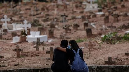 Familiares de vítima de covid-19, sepultada no Rio de Janeiro, se apoiam em cemitério em imagem de abril de 2021