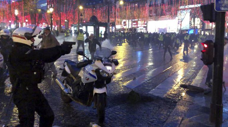 Policial tenta dispersar manifestantes na avenida Champs Elysées, em Paris