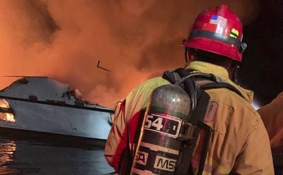 Um bombeiro trata de extinguir o incêndio declarado nesta segunda-feira em um barco em Califórnia.