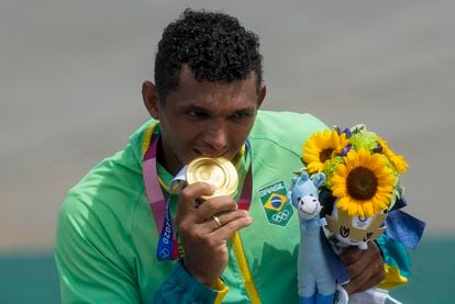 Isaquias Queiroz morde sua medalha de ouro na canoagem.