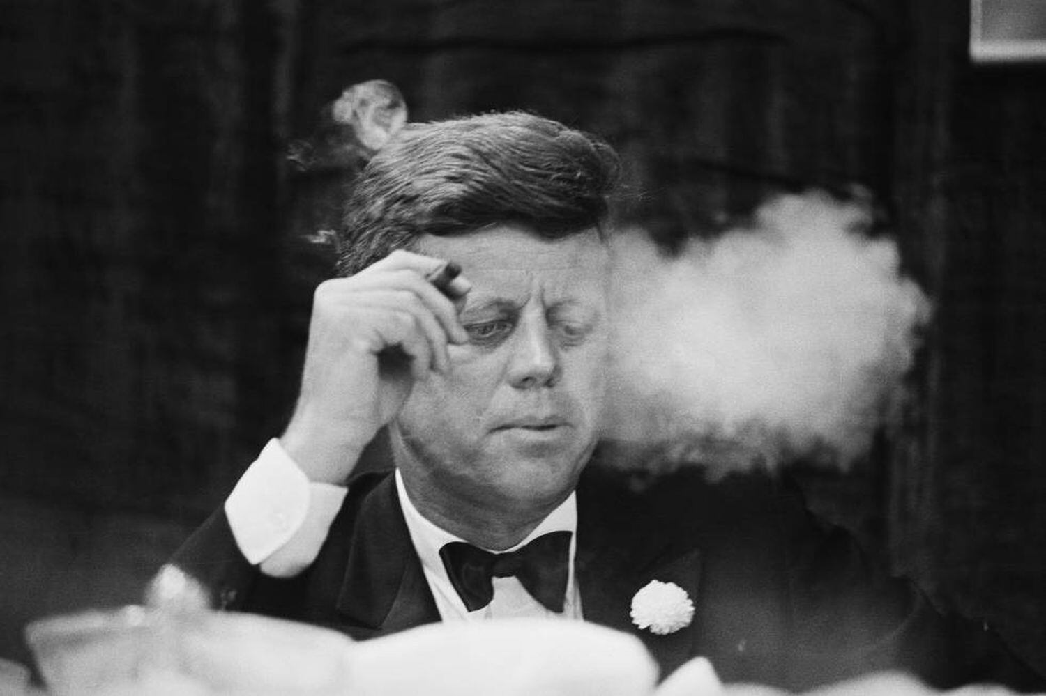O presidente John F. Kennedy fuma um charuto durante um jantar de arrecadação de fundos do Partido Democrata na Universidade de Boston.