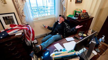 Un seguidor de Donald Trump, identificado como Richard Barnett, se sienta en el escritorio de la presidenta de la Cámara Baja, Nancy Pelosi, luego de irrumpir en el Capitolio.