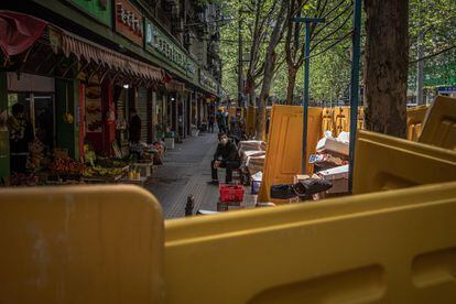 Um homem olha por trás das barreiras amarelas que ainda cercam muitas ruas da cidade.