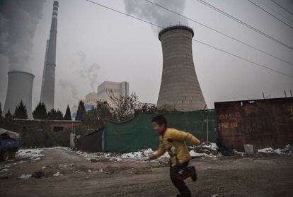 Um menino corre perto de uma central térmica de carvão em Pequim (China).