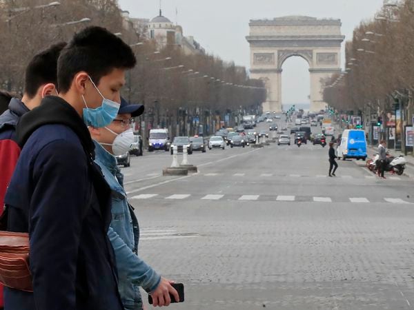 A group of tourists wearing protective masks cross the Champs Elysees avenue in Paris, Tuesday, March 17, 2020. France is imposing nationwide restrictions on how far from their homes people can go and for what purpose as part of the country's strategy to stop the spread of the new coronavirus. For most people, the new coronavirus causes only mild or moderate symptoms, such as fever and cough. For some, especially older adults and people with existing health problems, it can cause more severe illness, including pneumonia. (AP Photo/Michel Euler)