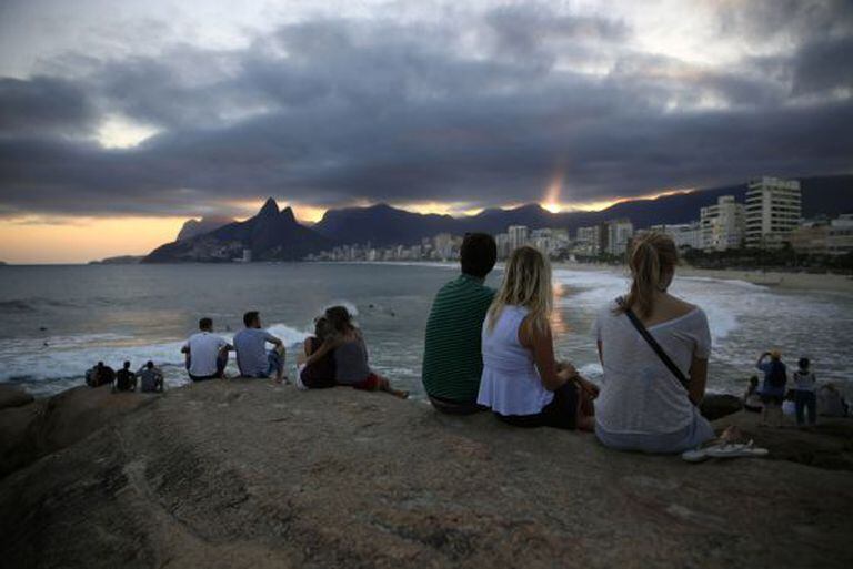 Turistas observam o pôr do sol no Arpoador, no Rio.