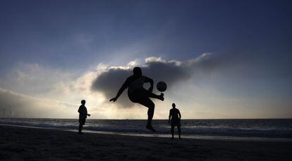 Homens jogam futebol na praia de Copacabana.