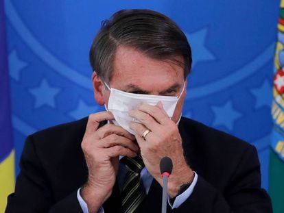 O presidente Jair Bolsonaro, colocando uma máscara de proteção durante um evento no Palácio do Planalto, em 18 de março. Aprovação do Governo se mantém estável.