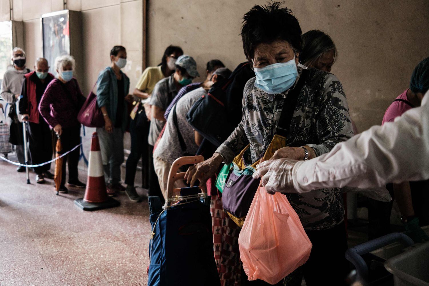 Pessoas fazem fila para pegar refeição doada em Hong Kong.