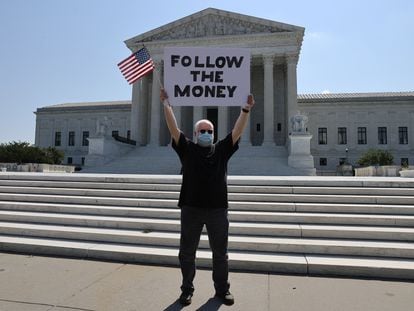 Manifestante diante da Suprema Corte com um cartaz em referência ao caso das finanças de Donald Trump,  na quarta-feira.