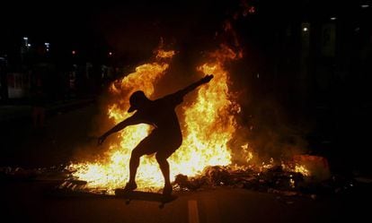 Jovem no skate em meio &agrave;s chamas ap&oacute;s a repress&atilde;o policial a protesto no Rio.