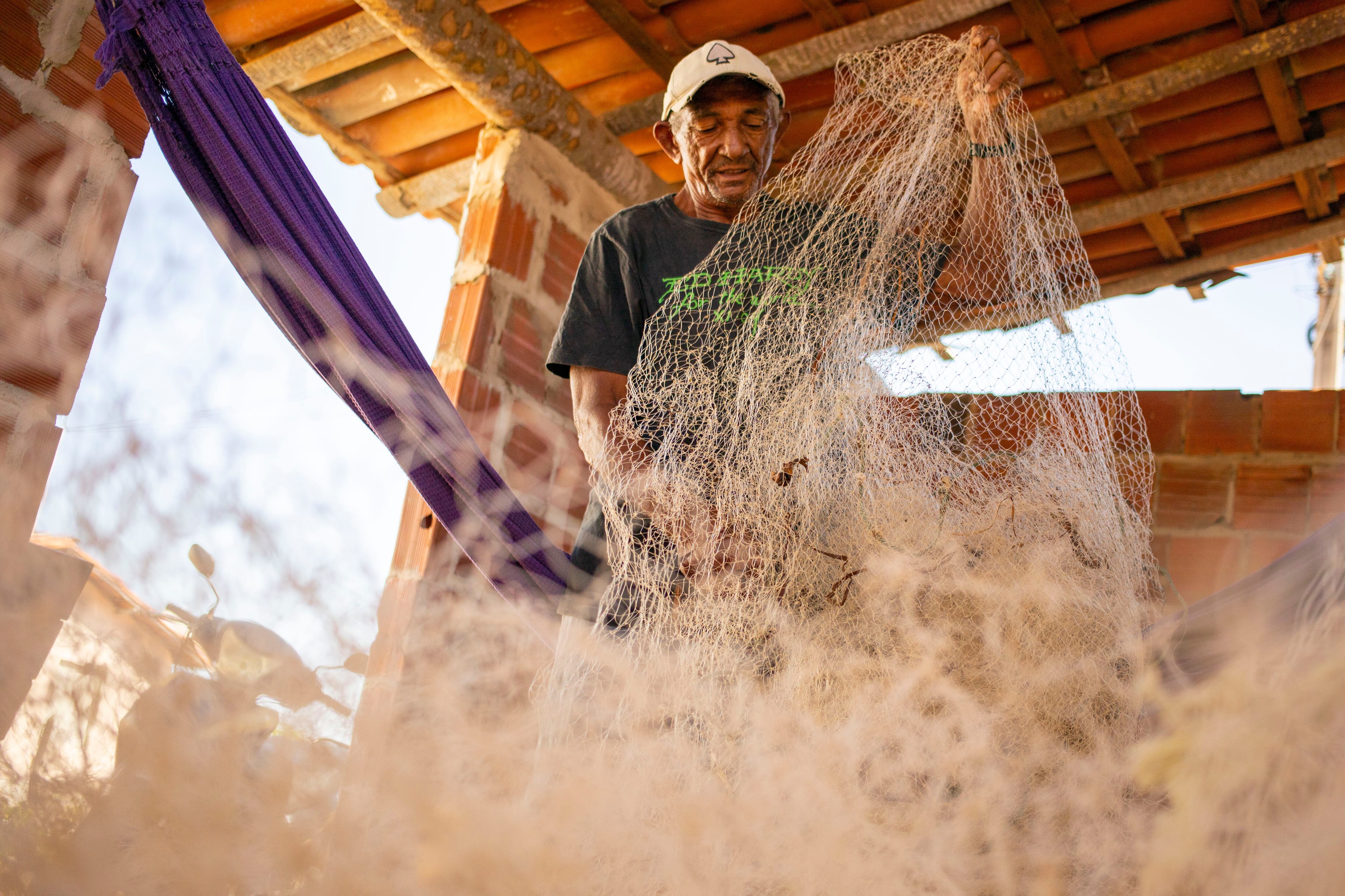 O pescador aposentado Antônio Ferreira de Oliveira, de 70 anos, organiza as redes de pesca em sua casa.