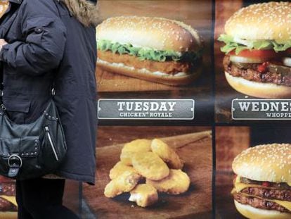 Uma mulher diante de um anúncio de fast food.