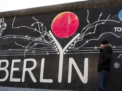 BERLIN, GERMANY - FEBRUARY 05: Vsitor passing a painting at the Berlin Wall at the East Side Gallery on February 5, 2018 in Berlin, Germany. Today tem been 10,316 days since the Berlin Wall officially fell, the same number of days that it stood between 1961 and 1989. The Berlin Wall, built by the communist authorities of East Germany, divided capitalist West Berlin from communist East Berlin and came to symbolize the Cold War between the western Allies, led by the United States, and the Eastern Bloc, led by the Soviet Union. (Photo by Carsten Koall/Getty Images)