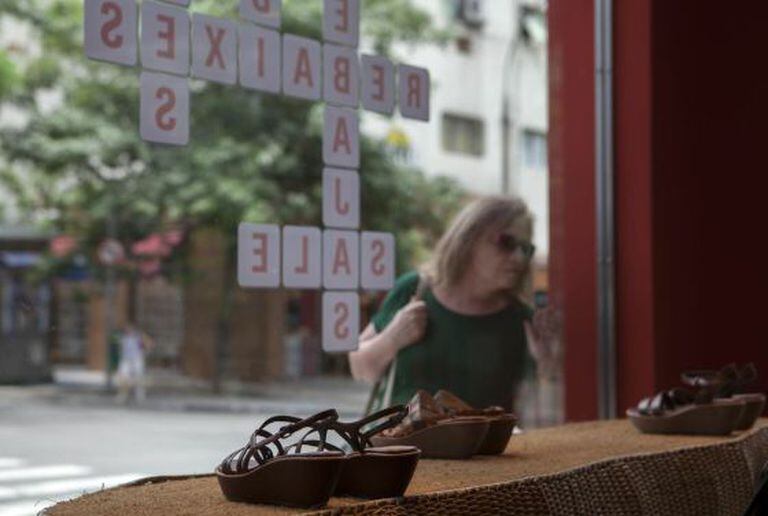 Mulher olha para vitrine em promoção em São Paulo.