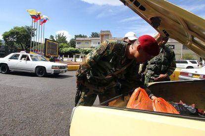 Militares venezuelanos revistam o conteúdo de um carro.