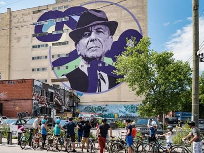 Ciclistas diante de um mural de Leonard Cohen em um edifício de Montreal, cidade natal do cantor canadense.
