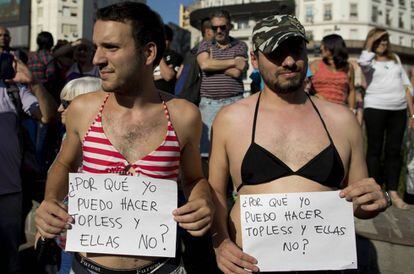 Dois homens que se uniram ao protesto com os cartazes: "Por que eu posso fazer topless e elas não?"