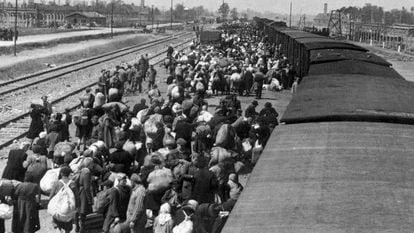Chegada de deportados a Auschwitz. Ao fundo, as chaminés dos fornos crematórios.