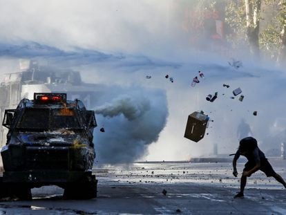 Um manifestante lança objetos em direção a um veículo blindado durante um protesto em Santiago do Chile.