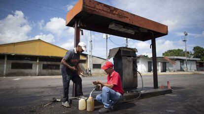 Dois homens enchem galões com gasolina em Chivacoa (Venezuela), em 13 de outubro de 2019.