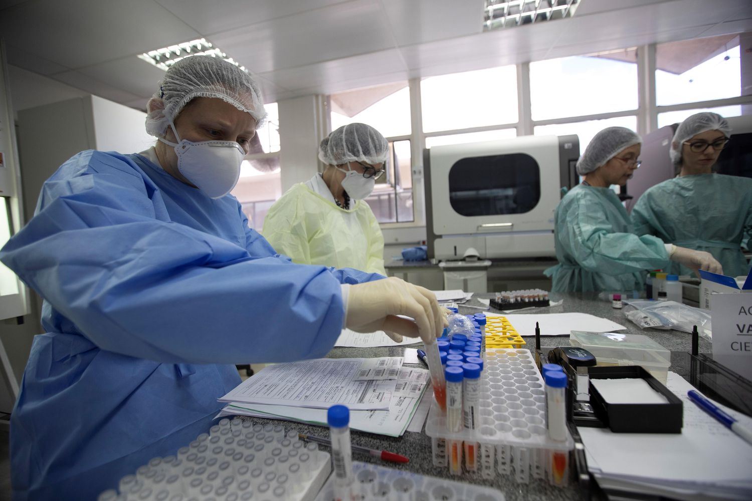 Trabalhadores do Laboratório Central de Saúde Pública de Brasília estudam testes para o Covid-19 nesta sexta-feira. Brasil prevê começar em breve os primeiros ensaios clínicos.