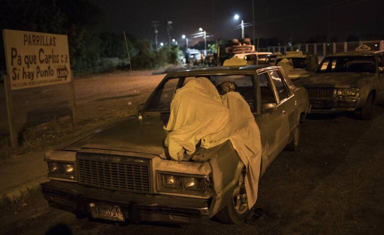 Um homem dorme sobre seu carro enquanto espera por gasolina em Maracaibo.
