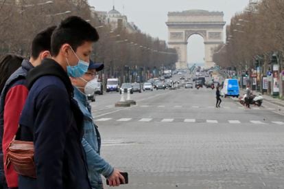 Turistas usam máscaras de proteção na avenida Champs Elysees, em Paris, no dia 17 de março.