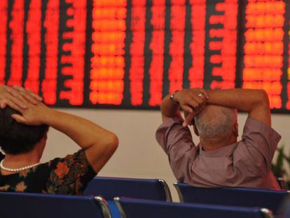 Dois investidores observam um painel com cotações da Bolsa na China.