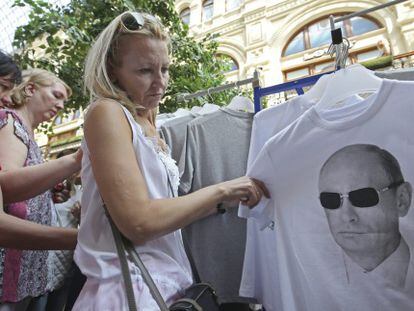 Uma mulher em Moscou observa uma camiseta com a fotografia do presidente russo.