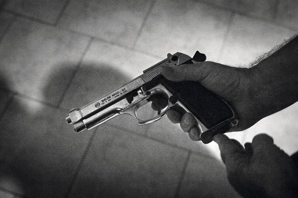 O pai de um rapaz de uma gangue mostra a pistola que deixa na mesa de cabeceira à noite, quando dorme.