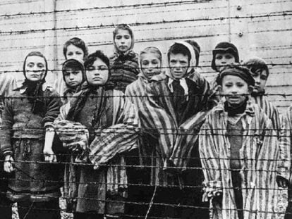 Um grupo de crianças atrás da cerca do campo nazista de Auschwitz.