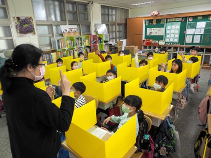 Alunos de uma escola em Taipei (Taiwan) usam máscaras e são separados por divisórias para prevenção do Covid-19.
