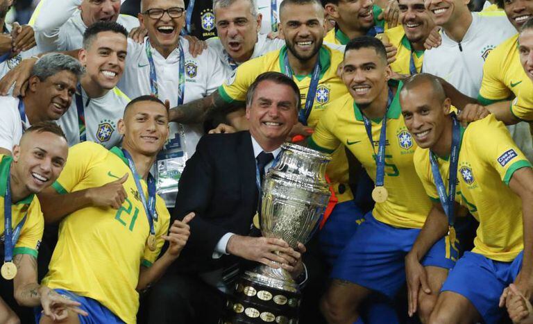 Bolsonaro posa com a taça ao lado dos jogadores da seleção.