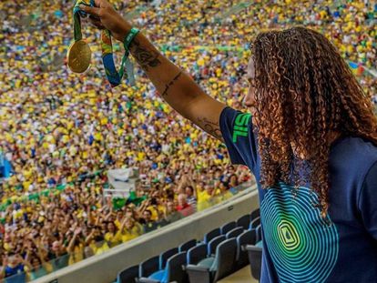 Rafaela Silva mostra sua medalha de ouro para os espectadores da partida entre a seleção feminina de futebol e Suécia.