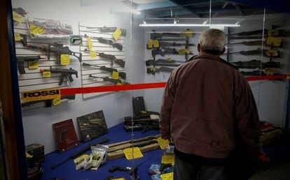 Homem observa vitrine com armas em São Paulo.