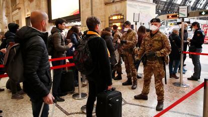 Agentes da polícia e soldados revistam passageiros em um posto de controle na estação central de Milão.