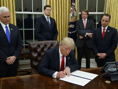 O presidente Donald Trump, no centro, assinando sua primeira ordem executiva, em 20 de janeiro.