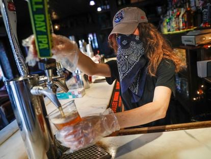 Garçonete serve uma cerveja em um bar de Nova York, em junho.