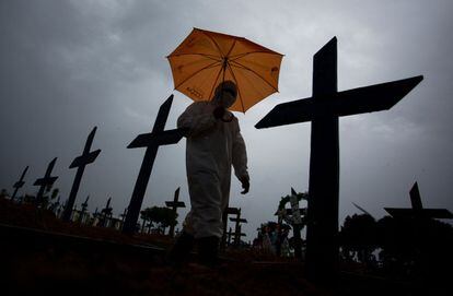Homem com roupa de proteção passa diante das tumbas com vítimas da covid-19 no cemitério de Nossa Senhora Aparecida, em Manaus (AM), em 25 de fevereiro.
