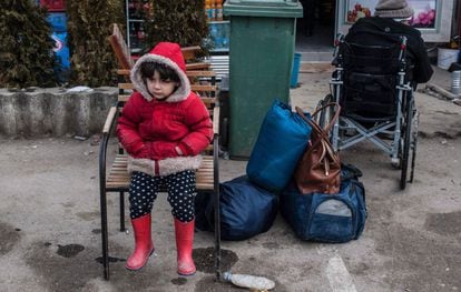 Criança espera sentada em frente a um campo de refugiados na Sérvia.