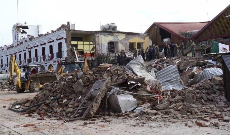 Bombeiros olham o que sobrou de um prédio municipal em Juchitan.