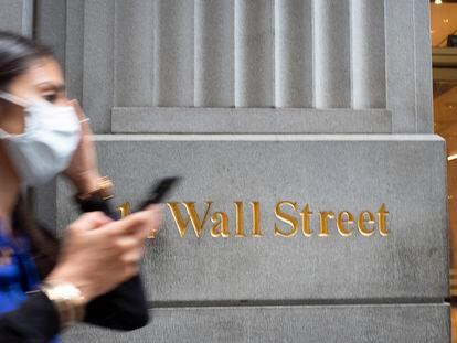 Mulher com máscara passa em frente a um edifício de Wall Street, o centro financeiro de Nova York.